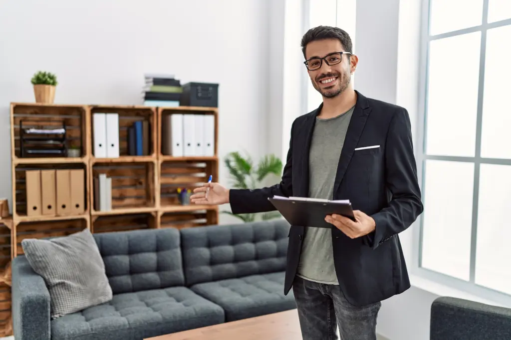 Young hispanic man having psychology session holding checklist welcoming patient at clinic